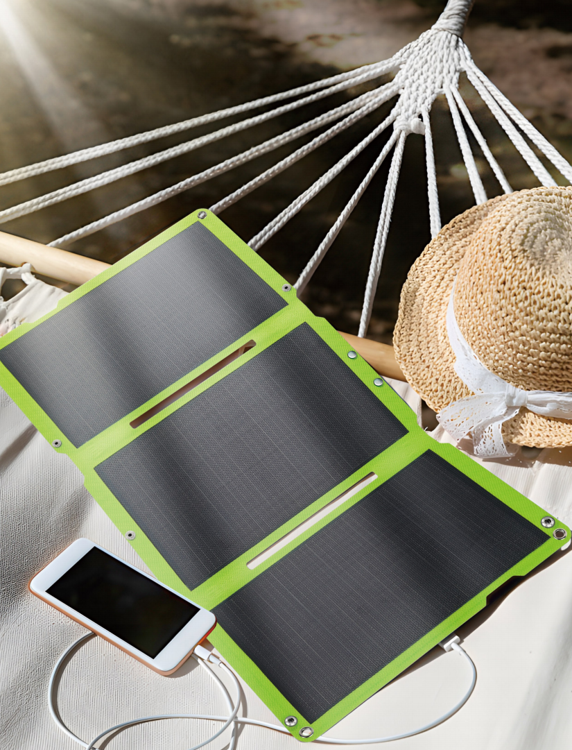 Portable solar panel charging a phone beside a hammock